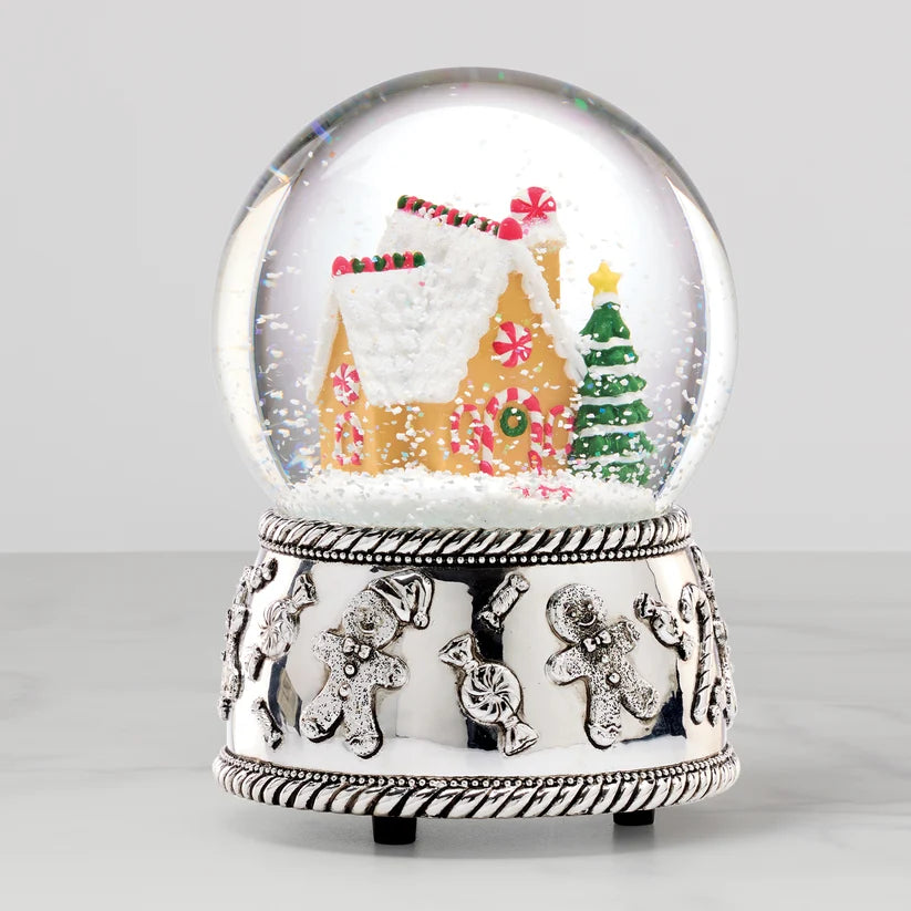 Christmas-themed snow globe with gingerbread house and tree on a white background