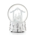 A clear glass Christmas snow globe with a silver-toned base, featuring a white nativity scene inside with a stable, star, and small figurines, photographed on a white background.