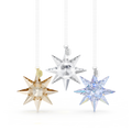 Three faceted crystal star ornaments hanging from white ribbons against a clean white background. One ornament is champagne gold, one is clear silver, and one is light blue with an iridescent finish.
