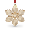 A faceted snowflake-shaped crystal ornament in a warm champagne beige color, suspended from a red ribbon with a gold tag engraved with '2026'.