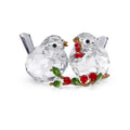 Crystal bird figurines with red berries on a branch against a white background
