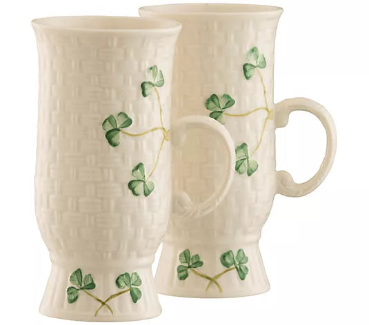 Two white mugs with green clover designs on a white background