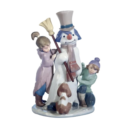 A glossy porcelain figurine of a snowman with children and a dog, with pastel color detailing.